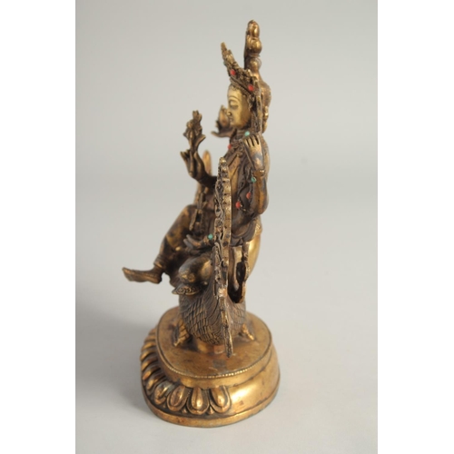 1237 - A CHINESE GILT BRONZE GOD seated on a dragon. 10ins high.