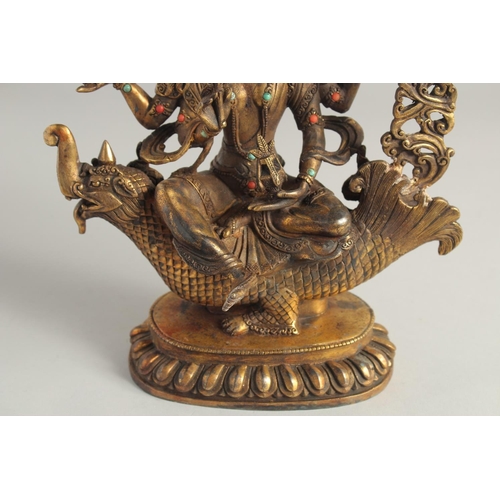 1237 - A CHINESE GILT BRONZE GOD seated on a dragon. 10ins high.