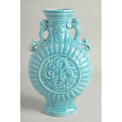 1256 - A CHINESE BLUE GLAZE TWIN HANDLED MOON FLASK with a central relief dragon motif. 33cm high.