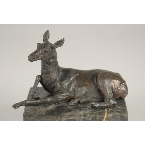 1296 - A SMALL BRONZE OF A DEER. 5.5ins long on a marble base.