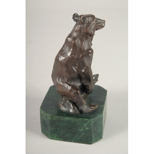 1297 - A SMALL BRONZE OF A BEAR. 5ins high on a marble base.