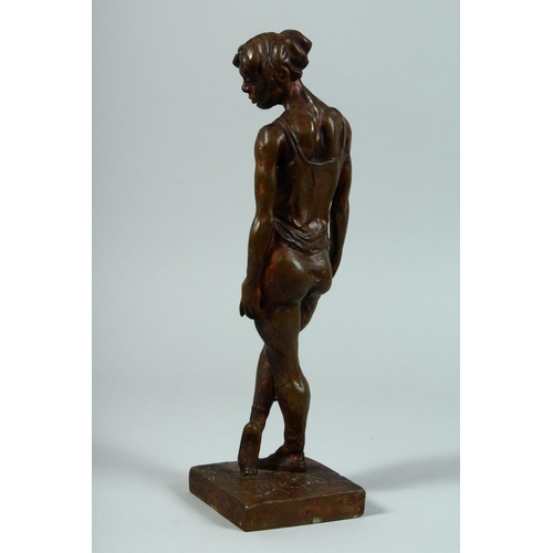 1328 - AFTER DEGAS A BRONZED STANDING FEMALE FIGURE on a square base. 13ins high.