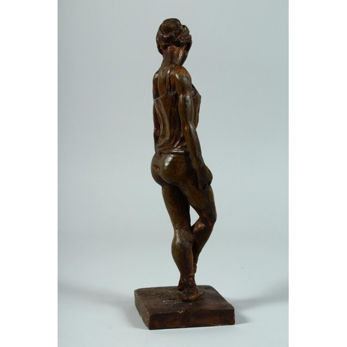 1328 - AFTER DEGAS A BRONZED STANDING FEMALE FIGURE on a square base. 13ins high.