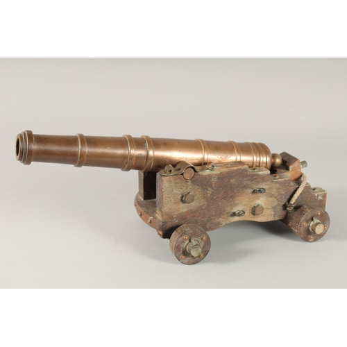 1343 - A GOOD SMALL BRONZE CANNON on a wooden carriage with four wooden wheels.