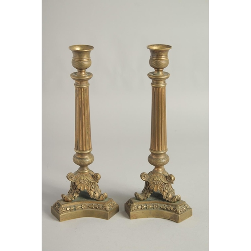 1412 - A PAIR OF EMPIRE ORNATE CANDLESTICKS on shaped triangular bases. 11.5ins high.