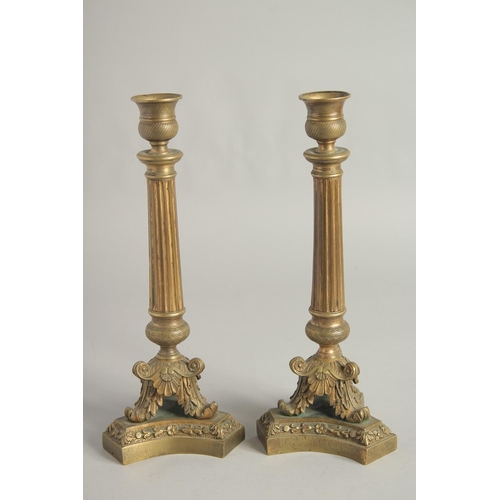 1412 - A PAIR OF EMPIRE ORNATE CANDLESTICKS on shaped triangular bases. 11.5ins high.