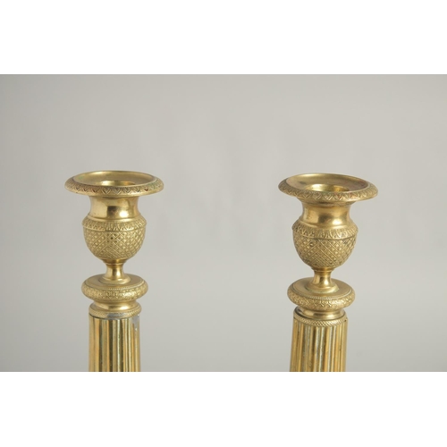 1413 - A PAIR OF EMPIRE ORNATE CANDLESTICKS on circular bases. 11ins high.