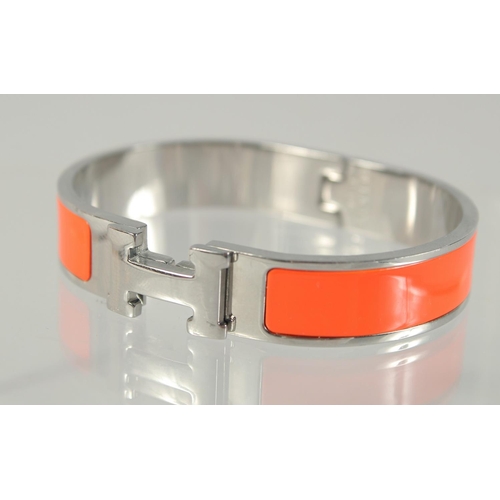 1482 - A HERMES ORANGE AND CHROME BANGLE.