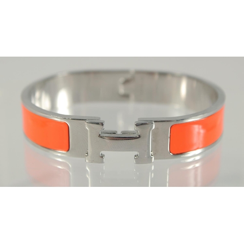 1482 - A HERMES ORANGE AND CHROME BANGLE.