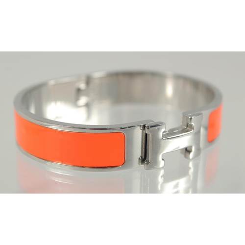 1482 - A HERMES ORANGE AND CHROME BANGLE.