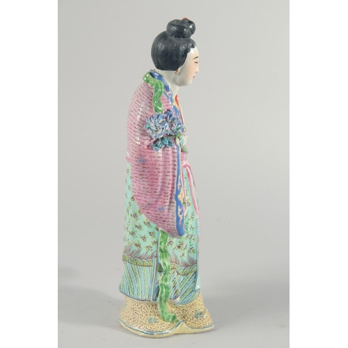 12 - A CHINESE FAMILLE ROSE PORCELAIN FIGURE, of a robed female holding flowers, 31cm high.