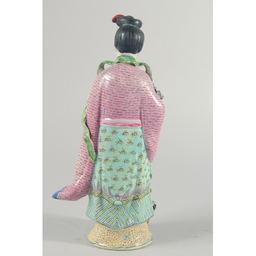 12 - A CHINESE FAMILLE ROSE PORCELAIN FIGURE, of a robed female holding flowers, 31cm high.