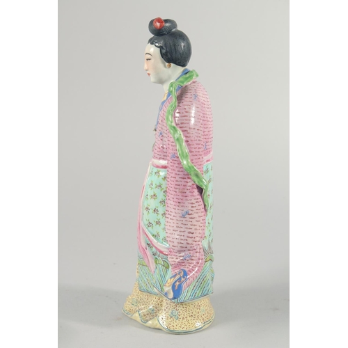 12 - A CHINESE FAMILLE ROSE PORCELAIN FIGURE, of a robed female holding flowers, 31cm high.