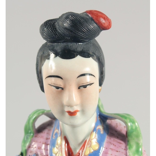 12 - A CHINESE FAMILLE ROSE PORCELAIN FIGURE, of a robed female holding flowers, 31cm high.