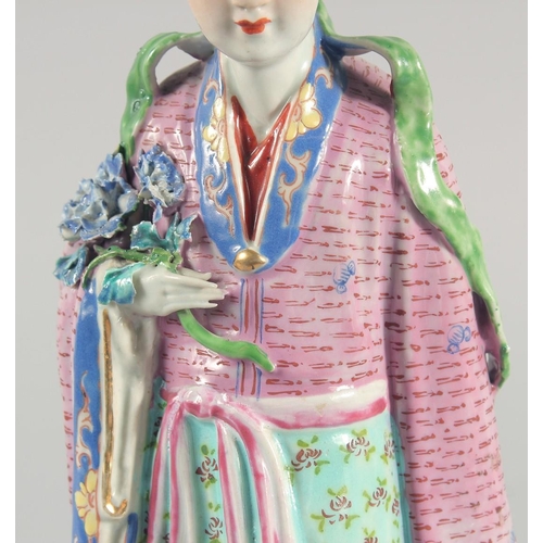 12 - A CHINESE FAMILLE ROSE PORCELAIN FIGURE, of a robed female holding flowers, 31cm high.