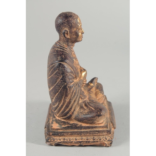 24 - A TIBETAN CARVED STONE SEATED FIGURE, with traces of gold paint, inscribed to the base, 18.5cm high.