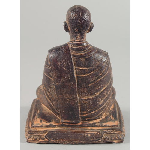 24 - A TIBETAN CARVED STONE SEATED FIGURE, with traces of gold paint, inscribed to the base, 18.5cm high.