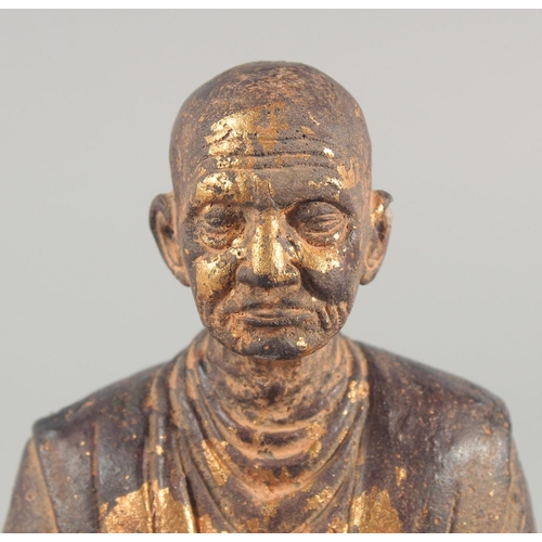 24 - A TIBETAN CARVED STONE SEATED FIGURE, with traces of gold paint, inscribed to the base, 18.5cm high.