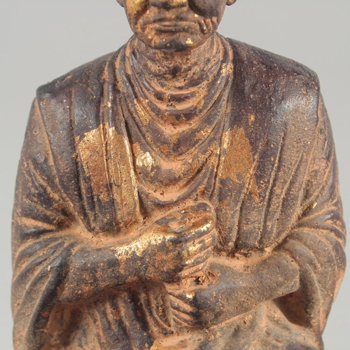 24 - A TIBETAN CARVED STONE SEATED FIGURE, with traces of gold paint, inscribed to the base, 18.5cm high.