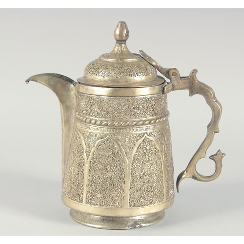 40 - AN ISLAMIC WHITE METAL LIDDED JUG, embossed and chased decoration, 25cm high.