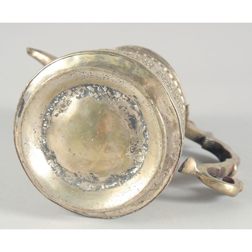 40 - AN ISLAMIC WHITE METAL LIDDED JUG, embossed and chased decoration, 25cm high.