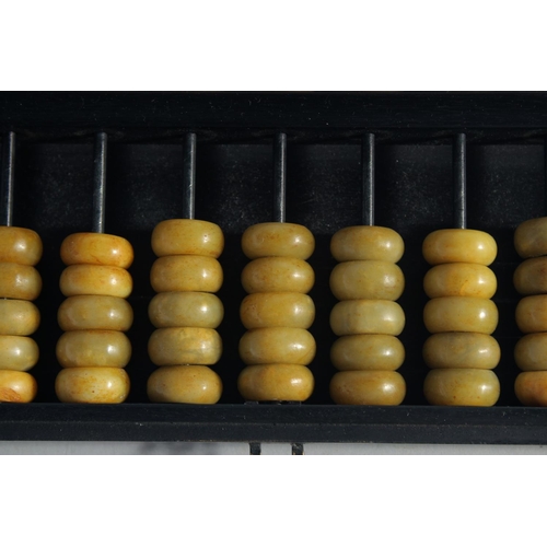 224 - A CHINESE HARDSTONE BEADED ABACUS contained within a hardwood box - the box inset with carved jade p... 