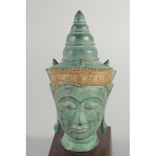 239 - A THAI METAL BUDDHA HEAD, with gilded headpiece and mounted to a wooden base, head 22cm high.