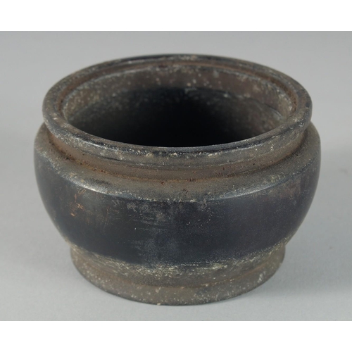 10 - A CHINESE BRONZE TWIN HANDLE CENSER, with relief decoration of stylised waves and raised on three wa... 