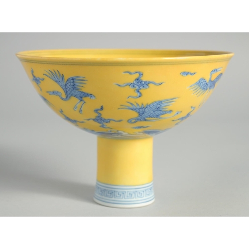 102 - A CHINESE YELLOW GROUND BLUE AND WHITE STEM CUP, the exterior decorated with cranes and stylised clo... 