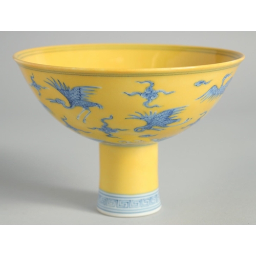 102 - A CHINESE YELLOW GROUND BLUE AND WHITE STEM CUP, the exterior decorated with cranes and stylised clo... 