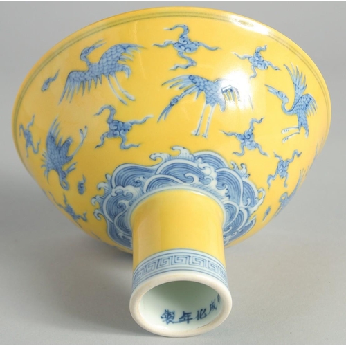 102 - A CHINESE YELLOW GROUND BLUE AND WHITE STEM CUP, the exterior decorated with cranes and stylised clo... 