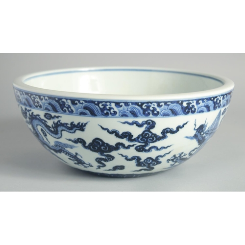 103 - A LARGE CHINESE BLUE AND WHITE PORCELAIN DRAGON BOWL, the dragons amongst stylised clouds beneath a ... 