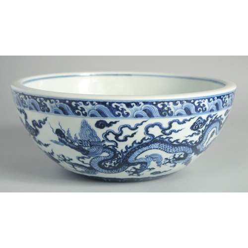 103 - A LARGE CHINESE BLUE AND WHITE PORCELAIN DRAGON BOWL, the dragons amongst stylised clouds beneath a ... 