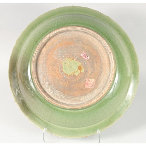 104 - A CHINESE LONGQUAN PETAL FORM CELADON CHARGER, with carved dragon to the centre, 41cm diameter.