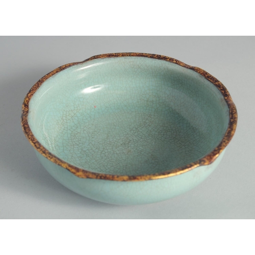 105 - A CHINESE CELADON PETAL FORM BOWL, with gilt rims and characters to the base, 18.5cm diameter.