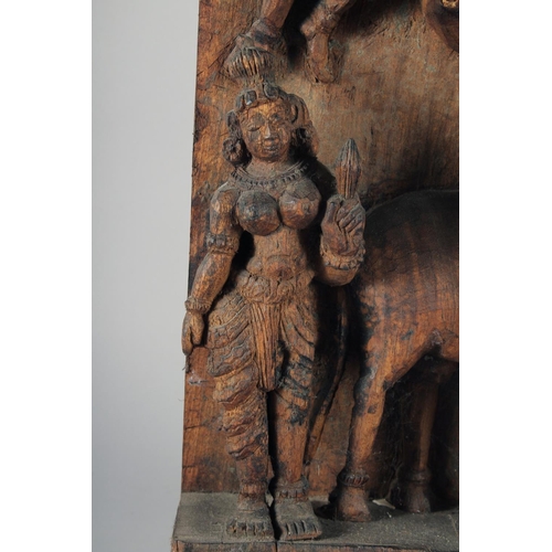 19 - A LARGE INDIAN CARVED WOODEN PANEL, with central deity playing a musical instrument surrounded by fo... 