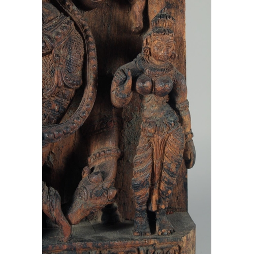 19 - A LARGE INDIAN CARVED WOODEN PANEL, with central deity playing a musical instrument surrounded by fo... 