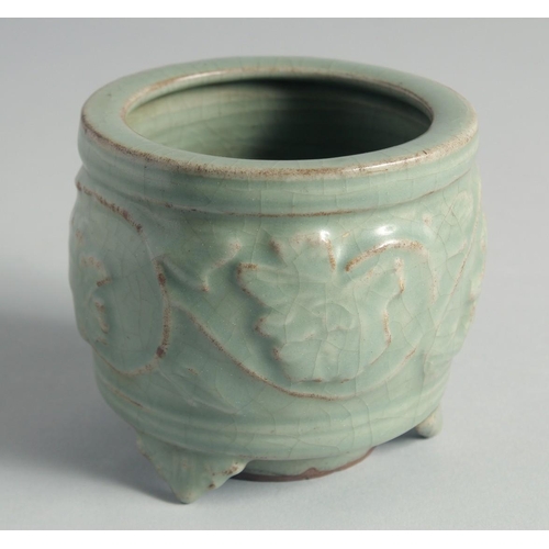 49 - A CHINESE CELADON GLAZE CENSER, relief-decorated with leaves and vine, raised on three feet, 10cm hi... 