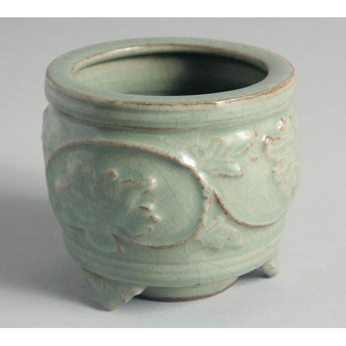 49 - A CHINESE CELADON GLAZE CENSER, relief-decorated with leaves and vine, raised on three feet, 10cm hi... 