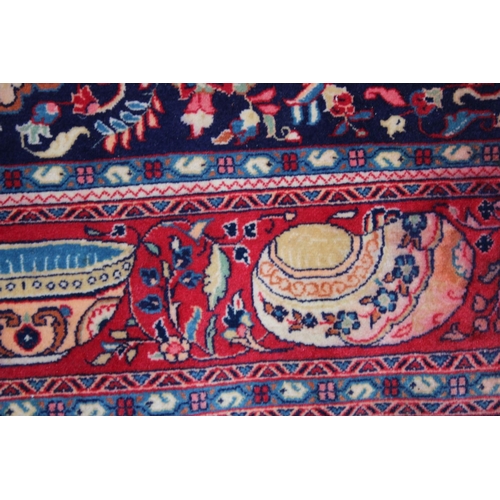 1014 - AN UNUSUAL PERSIAN CARPET, rich ground and deep red border, all with Persian and Islamic bowls, vase... 