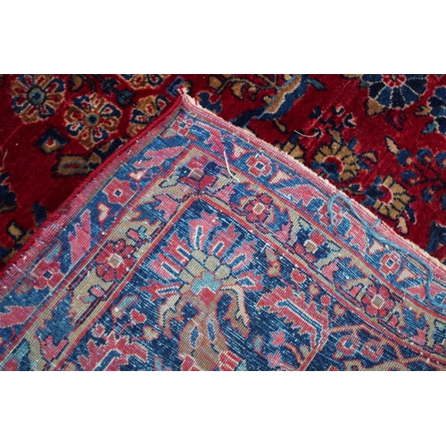 1020A - A LARGE PERSIAN CARPET, red ground with floral decoration (damage to one corner). 11'10