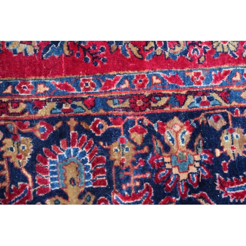 1020A - A LARGE PERSIAN CARPET, red ground with floral decoration (damage to one corner). 11'10