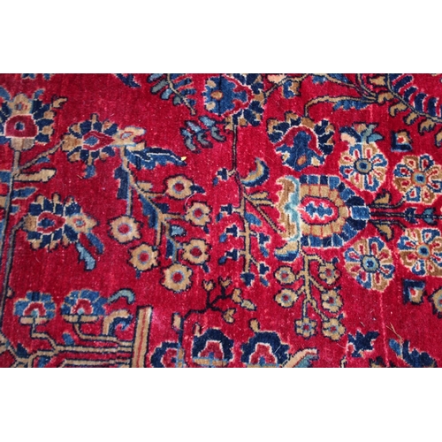 1020A - A LARGE PERSIAN CARPET, red ground with floral decoration (damage to one corner). 11'10