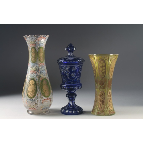 1043 - THREE VARIOUS BOHEMIAN GLASS VASES one with a cover. 13ins, 10ins & 9.5ins high.