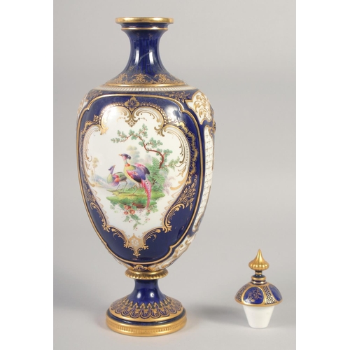 1083 - A ROYAL WORCESTER LARGE VASE painted with exotic birds in landscape on a cobalt blue ground in the m... 