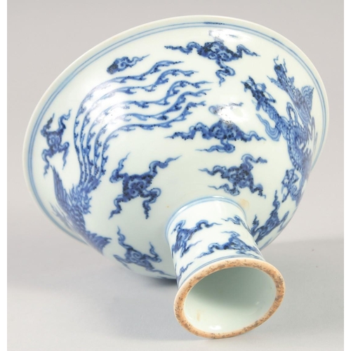 1137 - A CHINESE BLUE AND WHITE PORCELAIN STEM CUP with dragon and phoenix. 15.5cm diameter.