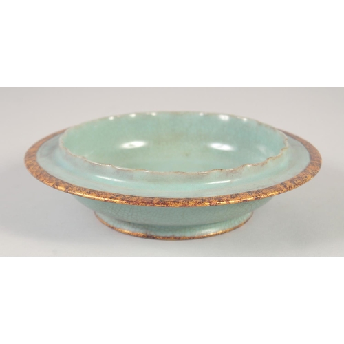 1138 - A CHINESE CELADON PETAL FORM DISH with incised gilt characters to the base. 20cm diameter.