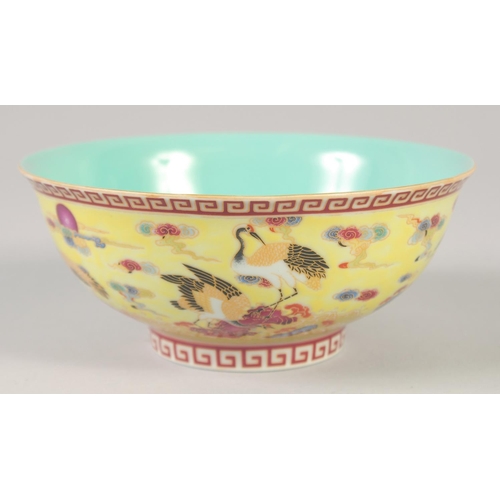 1144 - A CHINESE YELLOW GROUND FAMILLE ROSE BOWL decorated with cranes, six character mark to base. 15cm di... 