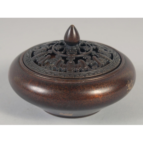 1174 - A CHINESE CIRCULAR BRONZE GOLD SPLASH CENSER AND COVER. 3.75ins diameter.