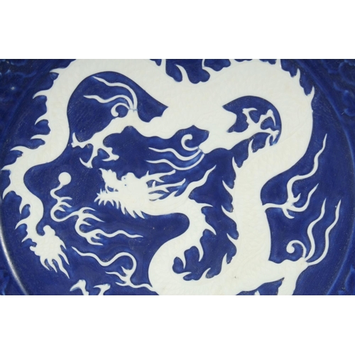 1185 - A LARGE CHINESE SACRIFICIAL BLUE DRAGON CHARGER, the centre with carved dragon in white; surrounded ... 